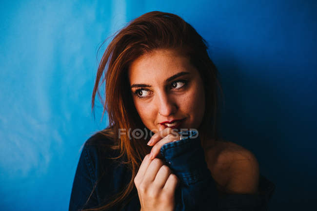 Attractive woman standing near blue wall — Stock Photo