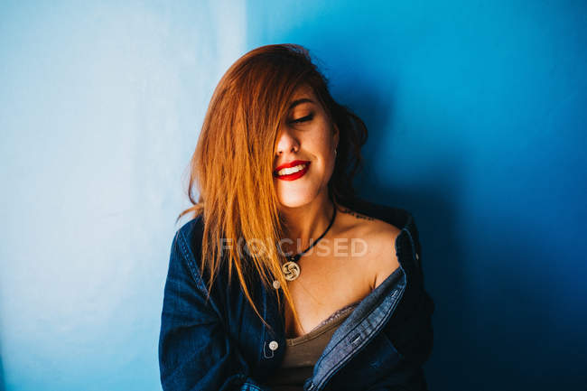Привлекательная женщина стоит у голубой стены — стоковое фото
