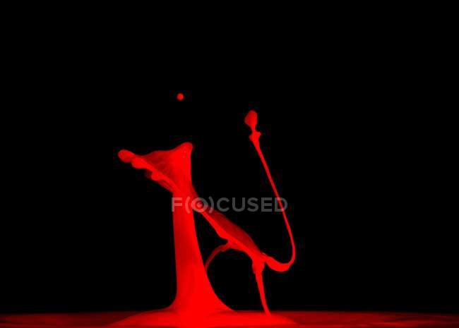 Nahaufnahme von Spritzer roter Flüssigkeit auf schwarzem Hintergrund — Stockfoto