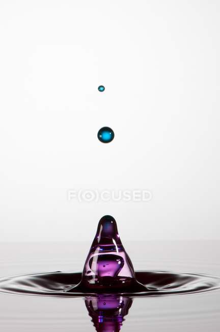 Respingo de líquido transparente de cor no fundo branco — Fotografia de Stock
