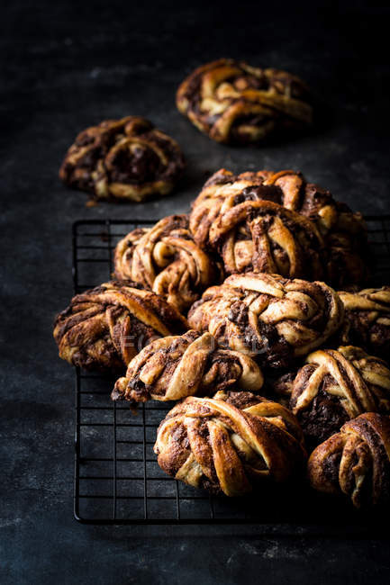Tas de délicieux petits pains au chocolat sur grille métallique sur fond sombre — Photo de stock