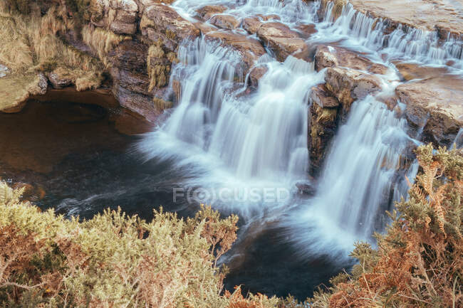Cascada sobre rocas altas en otoño - foto de stock
