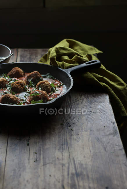 Padella con cavolfiore e polpette di quinoa in salsa sul tavolo di legno — Foto stock
