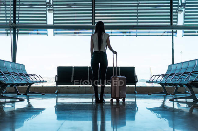 Молодая женщина с чемоданом возле сидений — стоковое фото