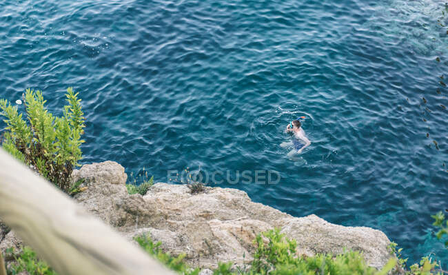 D'en haut homme méconnaissable en masque de plongée en apnée nageant dans l'océan bleu — Photo de stock