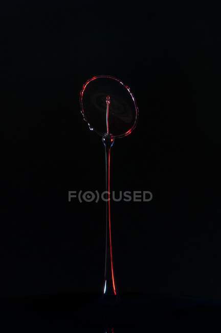 Close-up de respingo de líquido transparente de cor no fundo preto — Fotografia de Stock