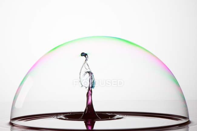Splash of colorful liquid into a bubble with high speed flash — Stock Photo