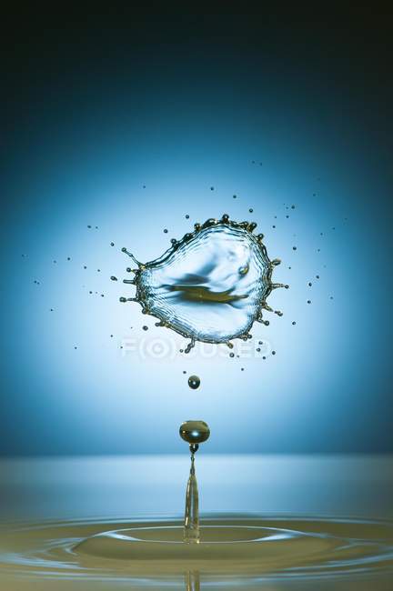 Closeup shot of splash of transparent liquid of color on blue background — Stock Photo