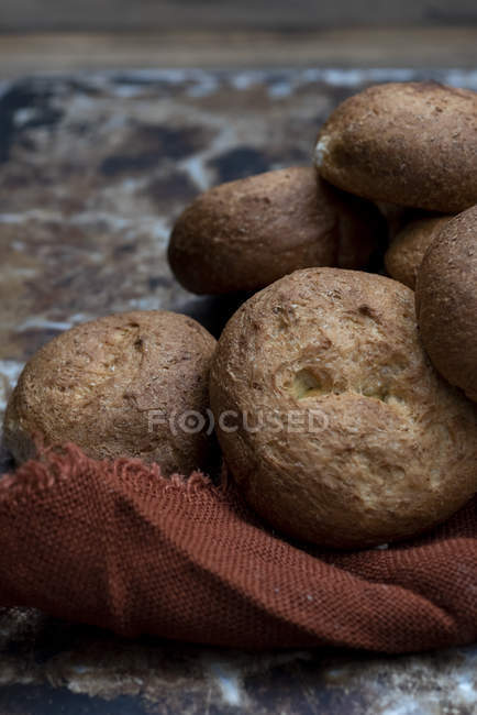 Petits pains frais cuits au four en tas sur une serviette brune — Photo de stock