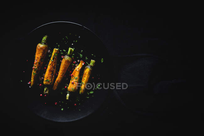 Cenouras assadas saudáveis com ervas e especiarias no fundo escuro — Fotografia de Stock