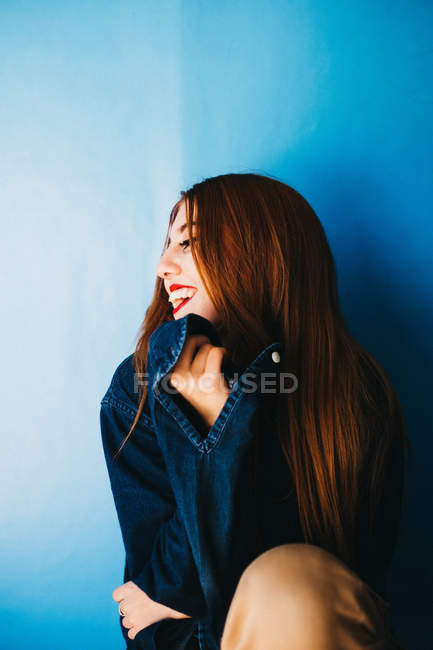 Donna attraente seduta vicino al muro blu — Foto stock