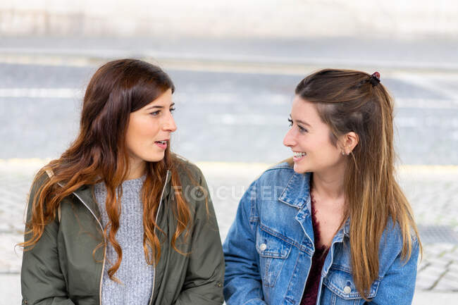 Young ladies in casual wear sitting on bench — Stock Photo