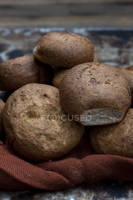 Petits pains frais cuits au four en tas sur une serviette brune — Photo de stock