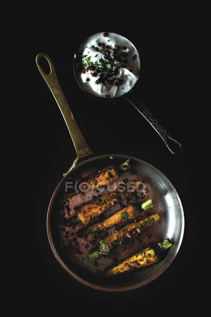 Gesunde geröstete Karotten mit Kräutern und Gewürzen auf schwarzem Hintergrund mit Sauce — Stockfoto