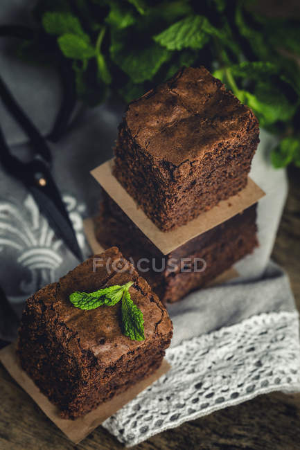 Pezzi di brownie al cioccolato con menta sul tavolo di legno con tovagliolo — Foto stock
