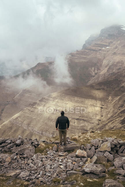 Homme debout sur la montagne entre le brouillard — Photo de stock