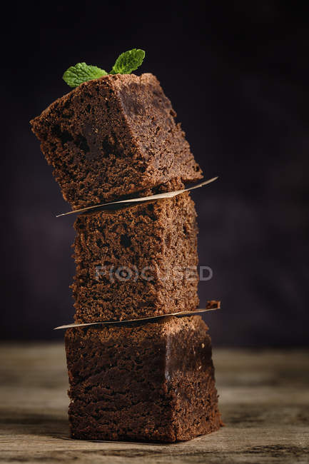 Складені шматочки шоколадного брауні з м'ятою на темному фоні — стокове фото