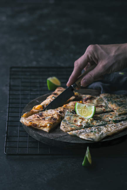 Hand of anonymous person cutting baked gozleme on wooden board — Stock Photo