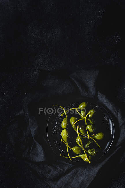 Câpres au vinaigre avec huile d'olive et sel. Flay supérieur ; vue supérieure. Sombre — Photo de stock
