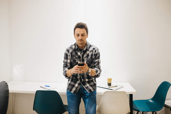 Young man with laptop talking on smartphone — Stock Photo