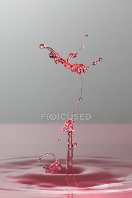 Closeup shot of splash of transparent liquid of color on gray background — Stock Photo