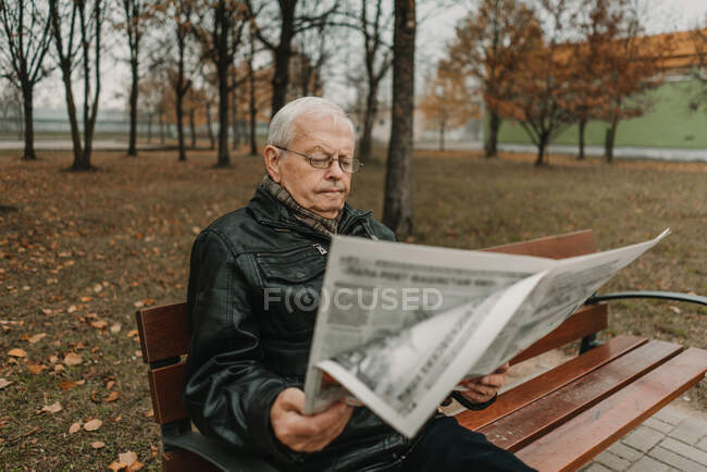 Elderly man reading newspaper in park — Stock Photo