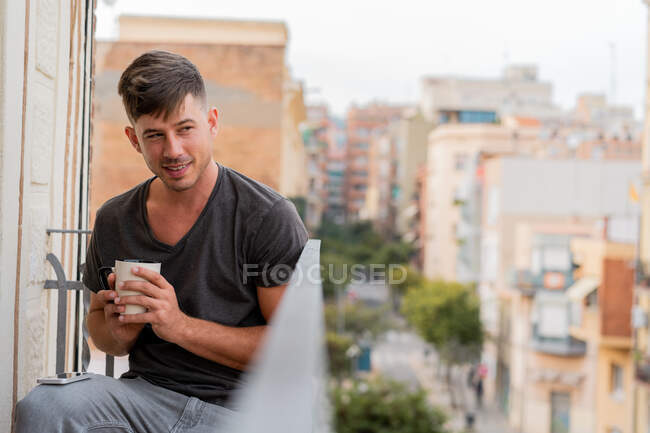 Розслабляючий чоловік має каву на балконі — стокове фото