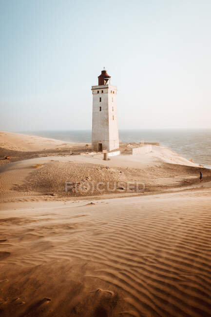 Rückansicht eines Touristen, der am Leuchtfeuer in Sanddünen steht — Stockfoto