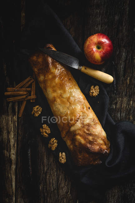 Strudel de manzana casera con nueces, pasas y canela sobre fondo de madera oscura — Stock Photo