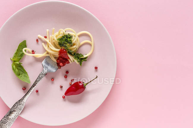 Spaghetti con salsa di pomodoro e pesto su fondo rosa — Foto stock