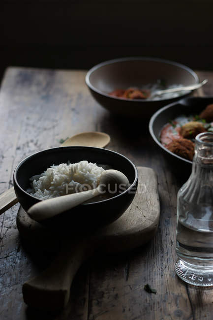 Schüssel Reis auf rustikalem Holztisch auf dunklem Hintergrund — Stockfoto