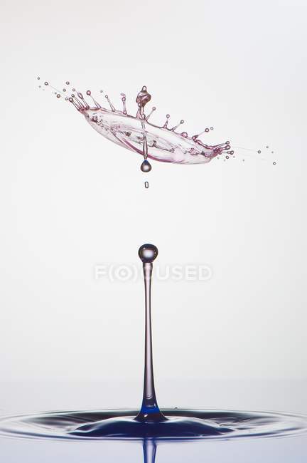 Splash of transparent liquid of color on gray background — Stock Photo
