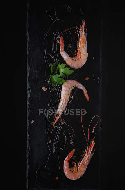 Black pasta with prawns served on slate on black background — Stock Photo