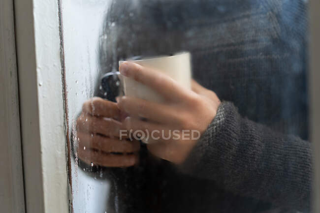 Hombre con café detrás de un vaso humeante - foto de stock