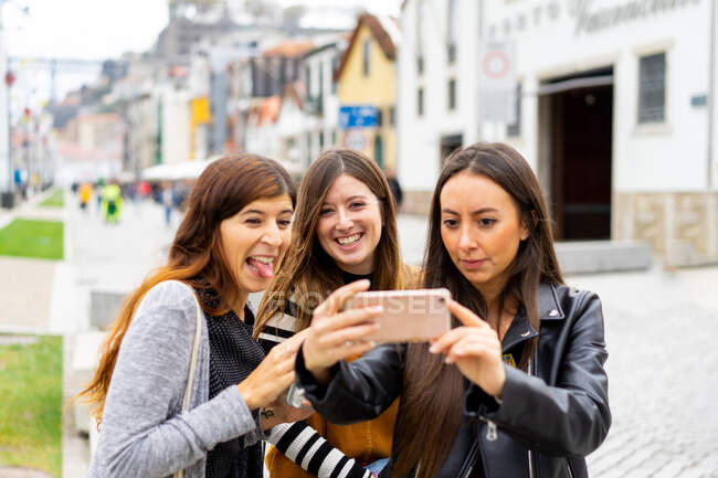 Jóvenes mujeres sonrientes tomando selfie en el teléfono inteligente en la pasarela - foto de stock