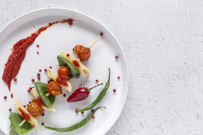 Макароны с помидорами и базиликом на тарелке на белом фоне — стоковое фото