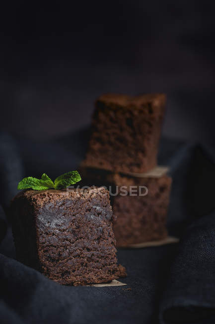Pezzi di brownie al cioccolato con menta su tessuto nero — Foto stock