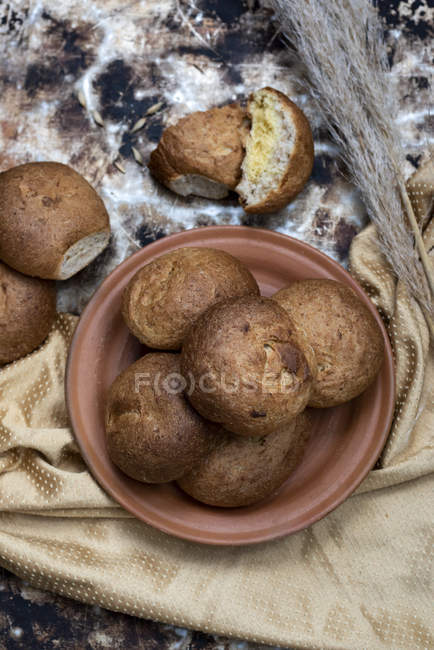 Panini appena sfornati su piatto marrone su sfondo rustico — Foto stock