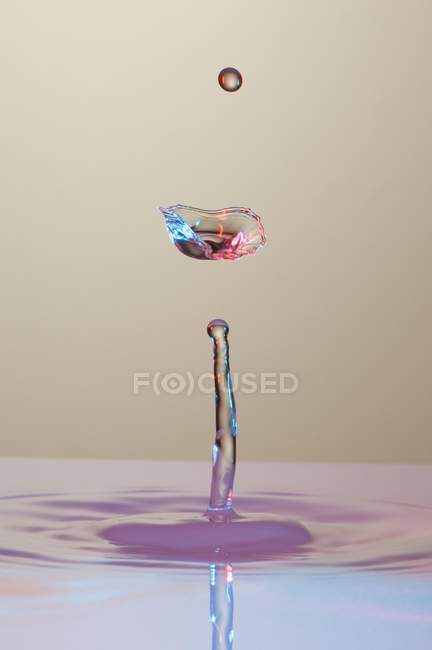 Closeup tiro de respingo de líquido transparente de cor no fundo cinza — Fotografia de Stock