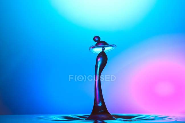 Closeup de respingo de líquido azul no fundo colorido abstrato — Fotografia de Stock