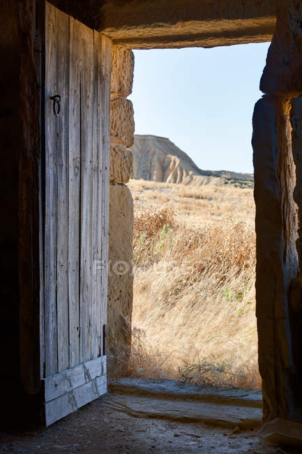 Blick auf trockenes Gelände durch die Eingangstür eines verwitterten Landhauses in Bardenas Reales, Spanien — Stockfoto