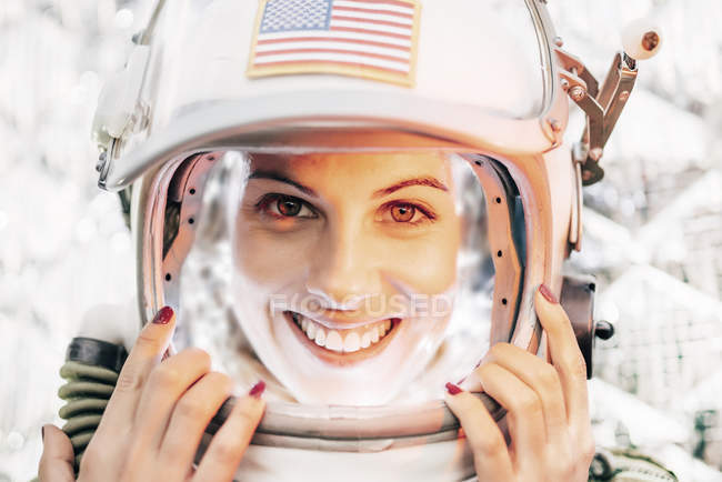 Chica sonriente con casco de espacio viejo y traje espacial sobre fondo de papel de aluminio - foto de stock
