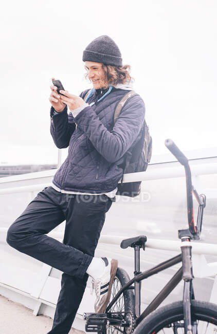 Молодий чоловік позує з мобільним і BMX велосипедом . — стокове фото