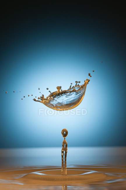 Closeup shot of splash of transparent liquid of color on blue background — Stock Photo