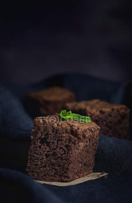 Pedazo de brownie de chocolate con menta en tela negra - foto de stock