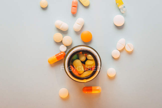 Разноцветные таблетки и капсулы разбросаны и коробки на белом фоне — стоковое фото