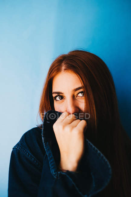 Приваблива жінка сидить біля блакитної стіни. — стокове фото