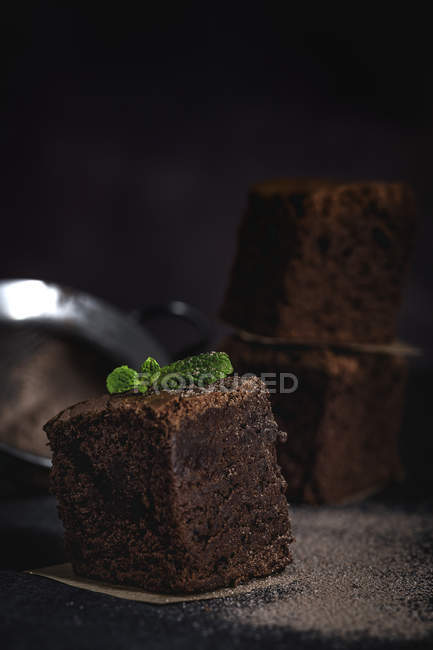 Pezzi di brownie al cioccolato con menta su sfondo scuro — Foto stock