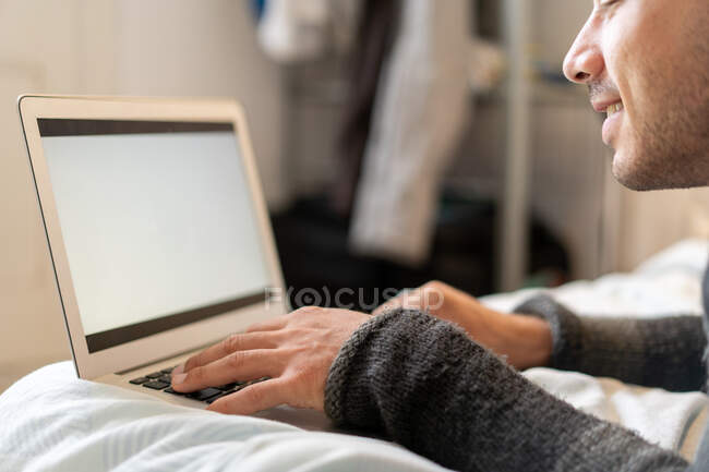 Homme se refroidissant sur le lit avec ordinateur portable — Photo de stock