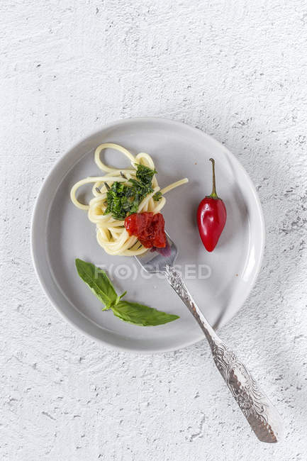 Spaghetti with tomato and pesto sauce on plate on white background — Stock Photo